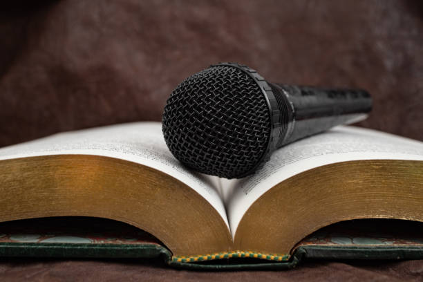 Microphone on a opened book with golden pages, audio book concept, soft focus